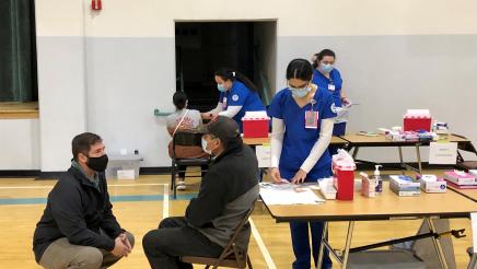 Assemblymember Dr. Joaquin Arambula talks with a man about to receive a COVID-19 vaccination at a clinic held on February 9, 2021 at the Victor P. Lopez Community Center in Orange Cove.